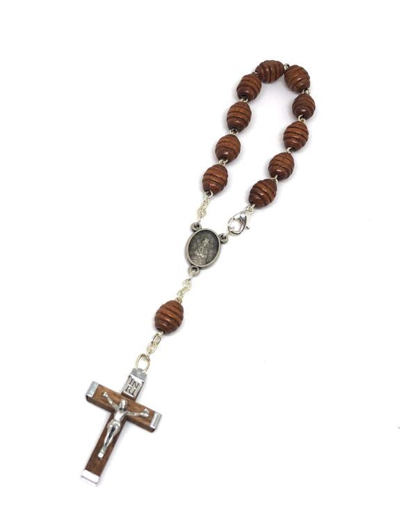 Rosario de mano de la Virgen del Rocío formado por 11 cuentas ovaladas de madera en color marrón. Incluye cruz fabricada en madera con Crucifijo de metal.